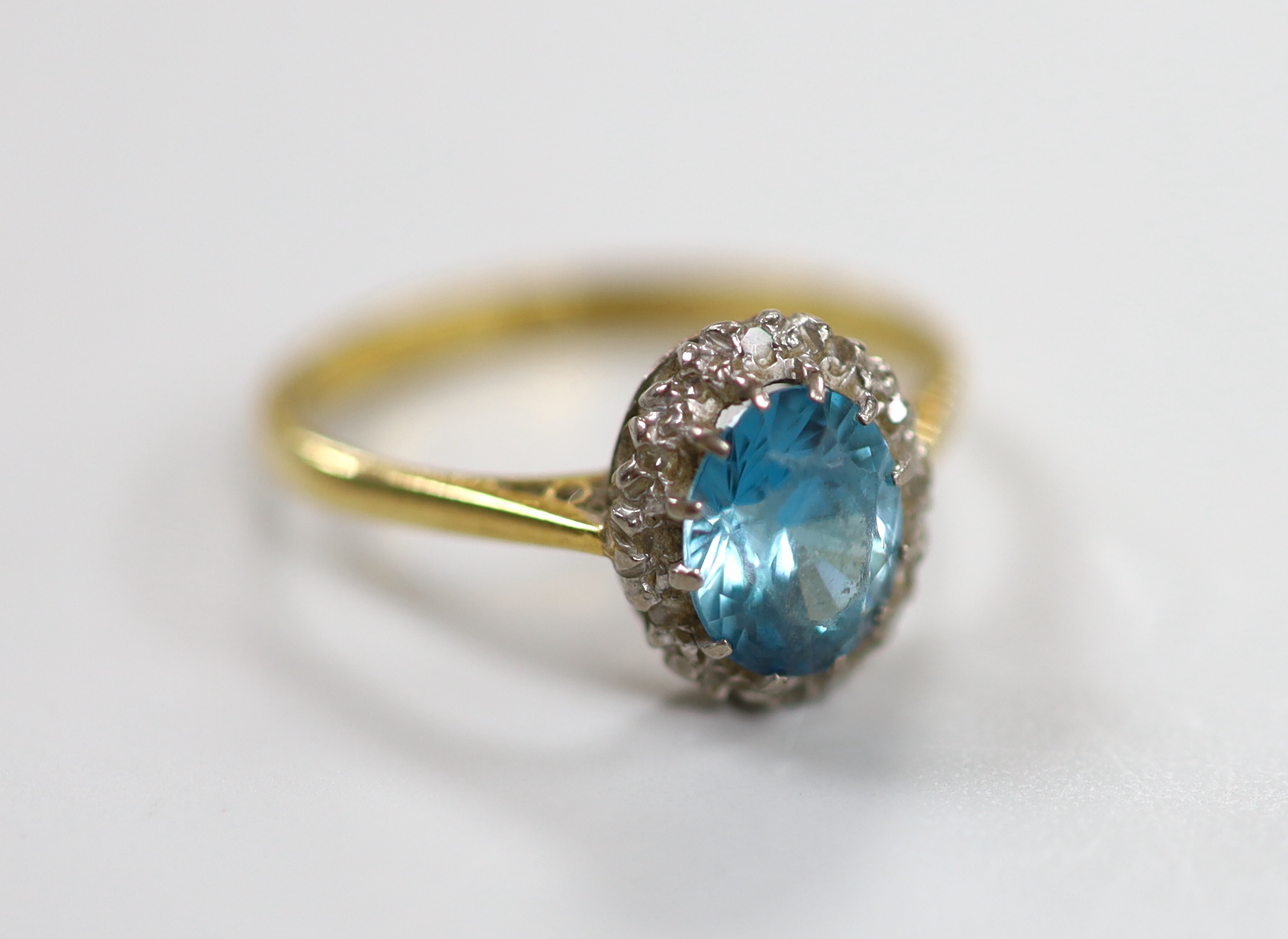 An 18ct blue zircon and diamond chip set oval cluster ring, size N, gross weight 3.1 grams.